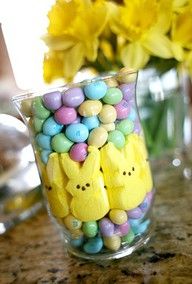 a vase filled with candy and peeppies on top of a table next to yellow flowers