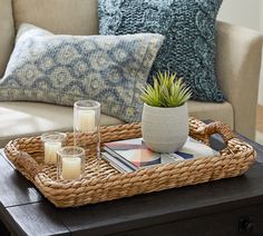 a wicker tray with candles on it in the middle of a living room area