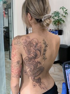 the back of a woman's body with tattoos on it