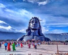 many people are walking around in front of a large statue