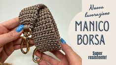 a person is holding up a crocheted keychain with two gold rings