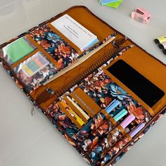 an open purse sitting on top of a table next to some pens and pencils