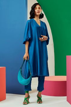 Royal blue straight kurta with scallop trim on the neckline and exaggerated puff sleeves. Comes with straight pants.
Components:2

Neckline:V neck
Sleeve Type:Puff Sleeves
Fabric:Silk
Color:Blue
Other Details:
Pleated back
Pant with scalloped trim at the hems
Note: Bag carried by the model is not for sale
Occasion:Work
Disclaimer: Product colour may slightly vary due to photographic lighting sources and  there can be slight difference in motif print placement due to running print fabric. - Aza F Ridhi Mehra, Silk Kurta, Pant Set For Women, Scallop Trim, Straight Kurta, Pakistani Dress Design, Scalloped Trim, Kurta With Pants, Print Placement