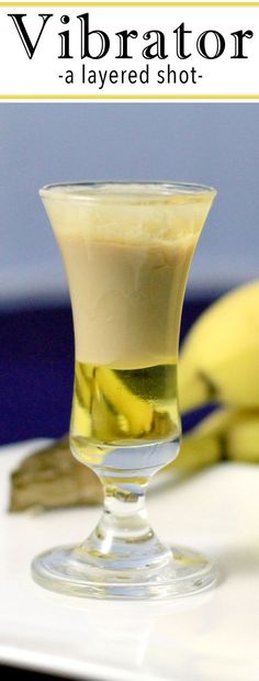 a glass filled with liquid sitting on top of a white table next to bananas and a banana peel