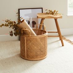 a basket that is sitting on the floor next to a table with a plant in it