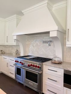 a stove top oven sitting inside of a kitchen next to white cabinets and counter tops