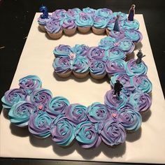 a cake shaped like the letter e with cupcakes on it