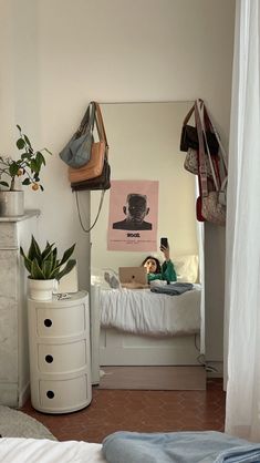 a person sitting on a bed in a room with white walls and flooring,