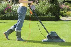 a woman is using a lawn mower in the grass