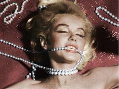 a woman laying on top of a red blanket covered in pearls and beads with her eyes closed