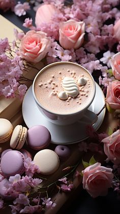 there is a cup of coffee and macaroons on the table with pink flowers