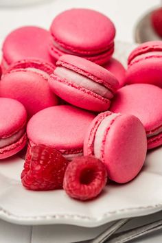 pink macaroons and raspberries on a white plate