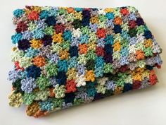 a multicolored crocheted dishcloth is laying on a white counter top