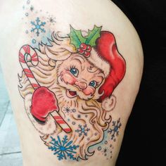 a woman's thigh with a christmas tattoo design on her leg and santa claus holding candy canes