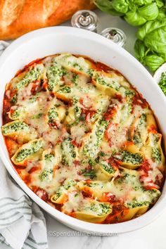 a casserole dish with spinach, cheese and sauce in it next to bread