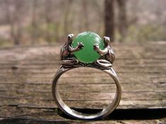 This original design is a sterling silver ring featuring two Frogs holding an 8 mm Aventurine stone. This ring has a solid shank that separates near the Frogs creating a secure mounting that shows the beauty of the stone. The Frogs are completely detailed on all sides and so happy to be holding this beautiful gem stone. Aventurine is widely known as Indian Jade and has the same luster and hardness as green Jade. This is a size 8 ring but I will honor any size request up to US size 13 (22.3 mm in Frog Ring, Frog Jewelry, Grass Valley, Indie Jewelry, Aventurine Stone, Funky Decor, Dope Jewelry, A Frog, Funky Jewelry