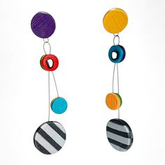 two colorful earrings hanging from strings on a white background, one with multicolored circles and the other with black stripes