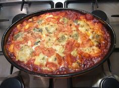 a pizza sitting on top of a stove covered in cheese