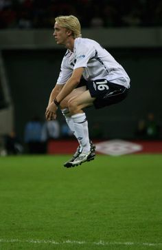 a man jumping up in the air on top of a soccer field with his legs spread out