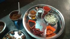 an assortment of food items on a metal platter with cups and spoons next to it