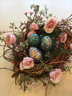 an arrangement of flowers and eggs in a nest