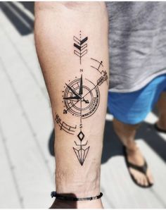 a man's arm with a compass tattoo on it and an arrow in the middle