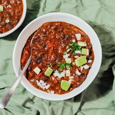 two bowls of chili with avocado, sour cream and cheese on the side