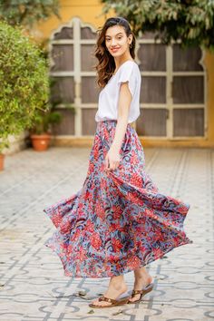 On this lively maxi skirt, printed on a base of periwinkle blue are pink blossoms and teal blue foliage. The cotton skirt features three tiers an elasticated waist and side seam pocket. India's Aftab finds the essence of spring and adds brings it life in this splendid skirt. Nature Skirt, Cotton Maxi Skirt, Blue Foliage, Empire Waist Maxi Dress, Cotton Maxi Skirts, Cotton Nightgown, Mid Calf Dresses, Caftan Dress, Cotton Maxi