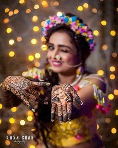 a woman with henna on her hands and lights in the back ground behind her