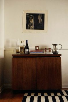 a wooden cabinet sitting on top of a hard wood floor next to a white wall