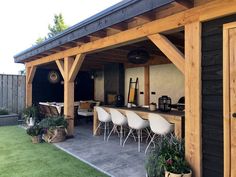 an outdoor bar with white chairs and potted plants on the outside patio, next to a wooden shed