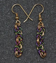 "These purple and green niobium byzantine or box chain earrings are a Mardi Gras range of colors in a lovely, thick box weave. These patterned woven chain earrings are an unusual and bright addition to your outfits. The links are made from 20 g. round wire jump rings that are 1/4\" (6 mm) outside diameter to a 1\" length (25 mm). They are then tumbled. The niobium links are then anodized for color. I then weave them by color into the pattern. The ear wires are gold fill. Please convo if you woul Handmade Green Byzantine Jewelry, Woven Chain, Purple And Green, Chain Earrings, Box Chain, Purple Green, Jump Rings, Ear Wires, Bright Colors