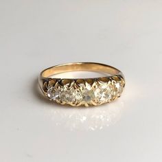 a yellow gold ring with five diamonds on the side, sitting on a white surface