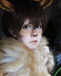 a woman with brown hair and horns on her head is wearing a fur collared coat