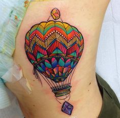 a colorful hot air balloon tattoo on the side of a woman's ribcage