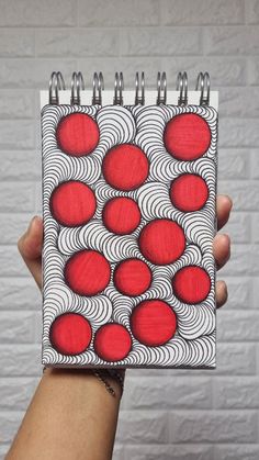 a hand holding up a spiral notebook with red circles on it