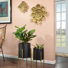 three planters are on the floor in front of a pink wall with gold accents