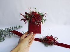 a hand holding a red ribbon with flowers on it