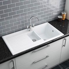 a white sink sitting under a window next to a counter top with black granite on it