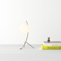 a table lamp sitting on top of a book next to a vase and a light bulb