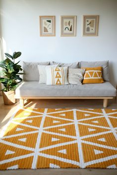 a living room filled with furniture and pillows on top of a wooden floor next to a window