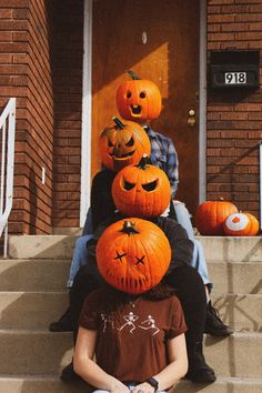 a group of people sitting on the steps with pumpkins in front of their heads