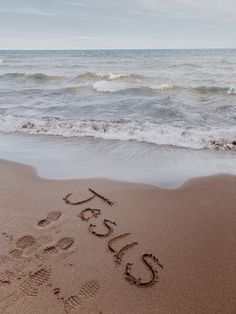 someone wrote their name in the sand at the beach with waves coming in and out