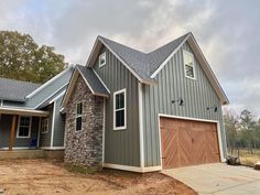 a gray house with two garages on the front and one door is open to let in light