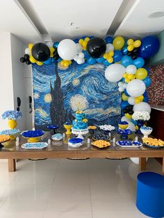 a table topped with blue, yellow and white desserts next to a wall painting