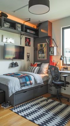 a bedroom with a bed, desk and computer monitor on the wall next to it