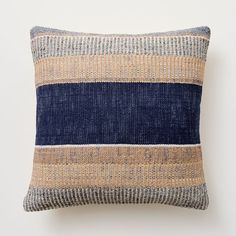 a blue and tan striped pillow sitting on top of a white wall