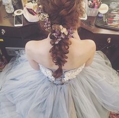 a woman sitting in front of a mirror wearing a blue dress with flowers on it