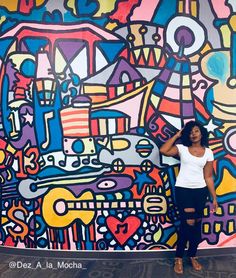 a woman standing in front of a colorful wall