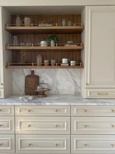 a kitchen with white cabinets and marble counter tops, gold pulls on the door knobs